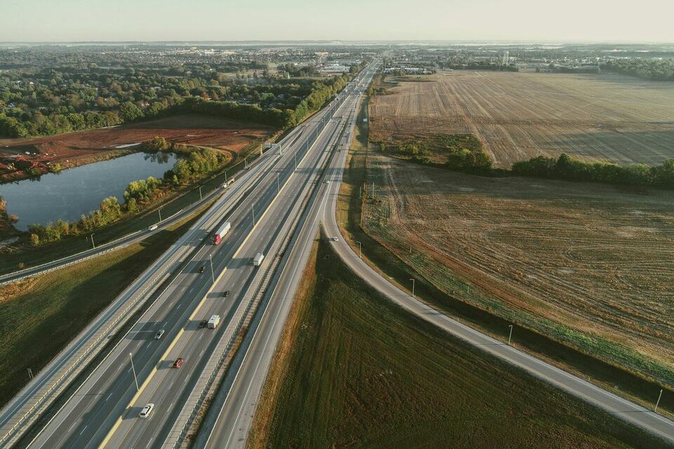 Aerial view of a divided interstate highway stretching past farm fields toward the horizon