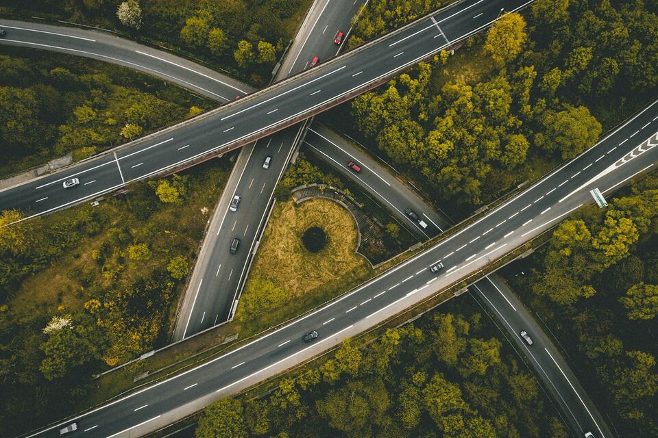 Aerial view of a highway interchange cutting through dense green forest