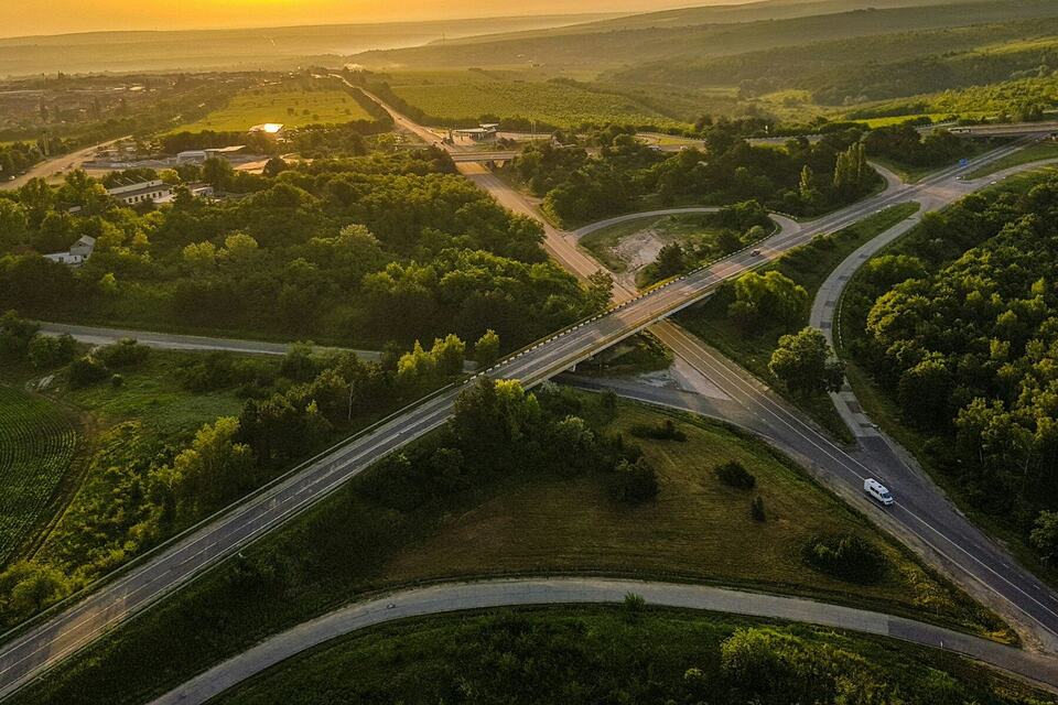 Aerial view of a highway interchange winding through green hills at sunset