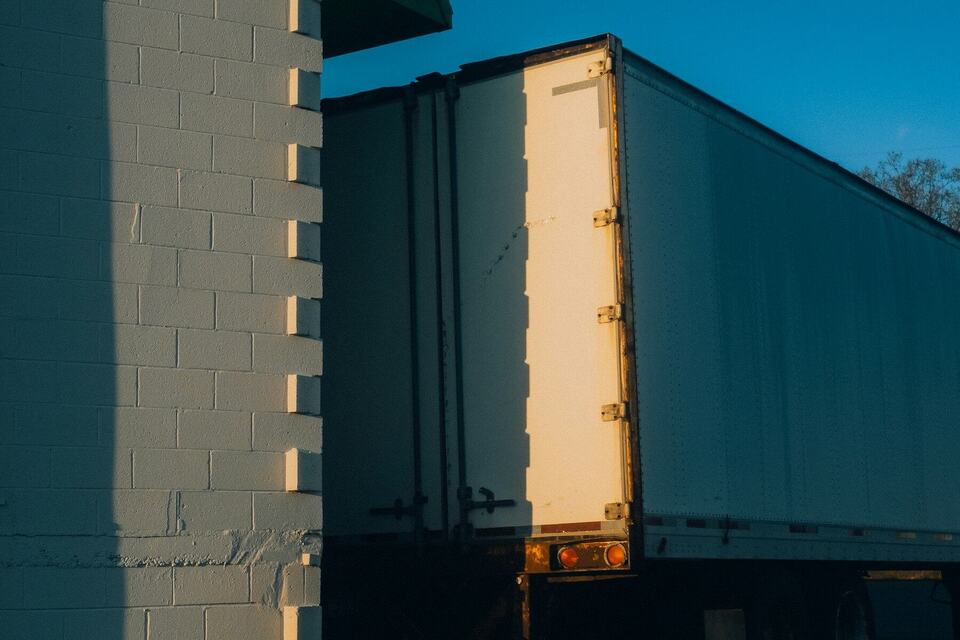 Evening light on the side of a semi-trailer parked beside a brick wall
