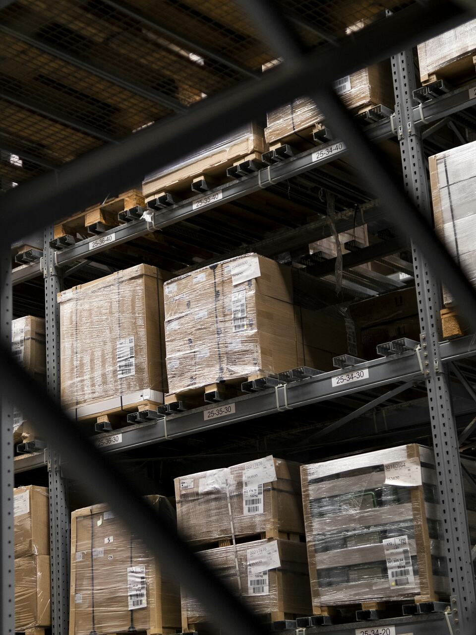 Warehouse racking stacked with shrink-wrapped pallets of cartons